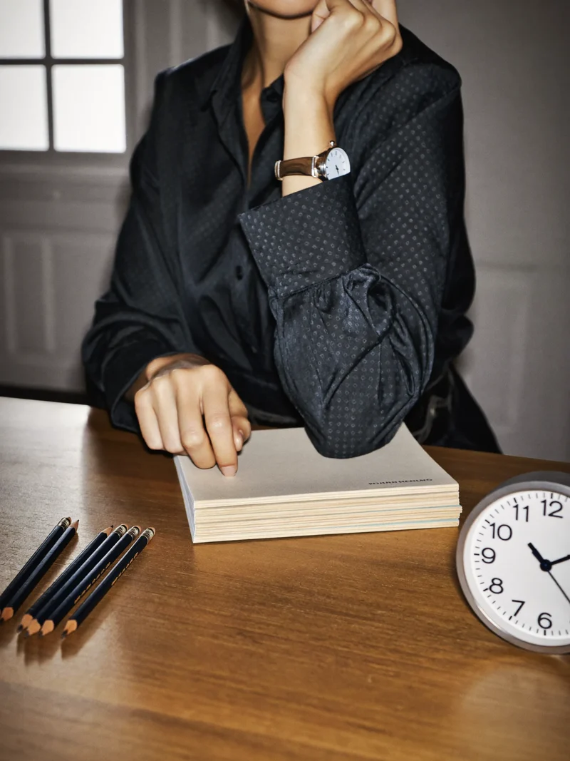 Lernender mit leeren Übungsheften, Stiften und Uhr bei der Prüfungsvorbereitung